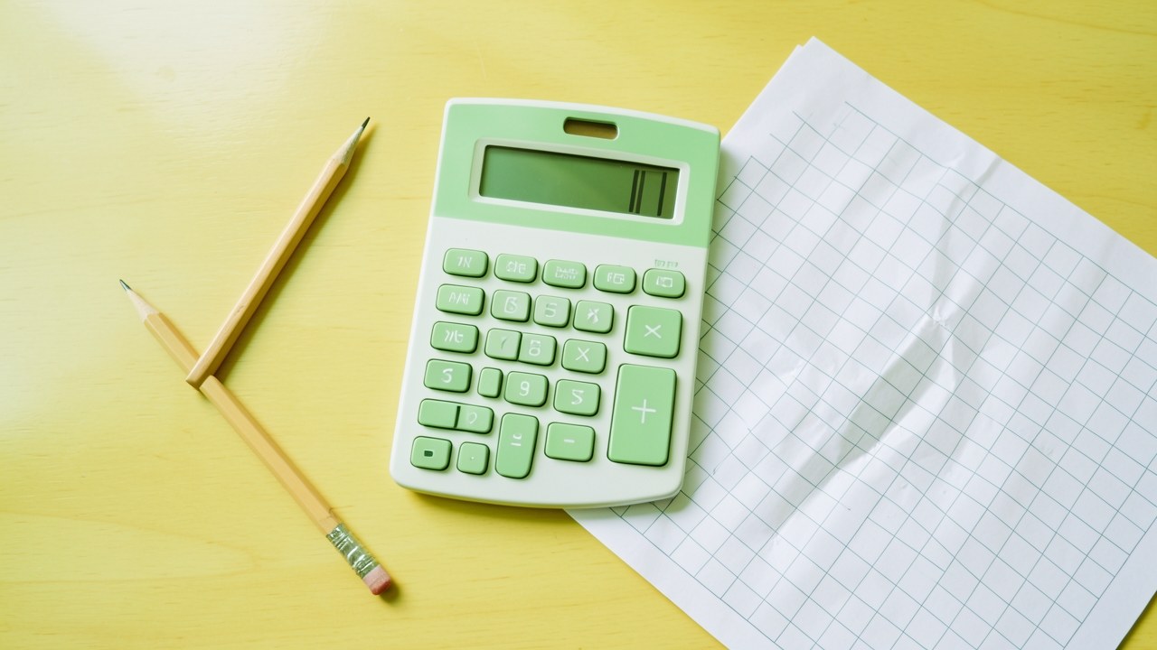 A calculator and a pencil on a sheet of paper with a table (blank), suggesting manual calculation